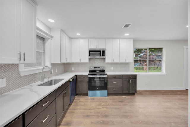 7401 Trimble Dr, Fort Worth, TX 76134 - kitchen with appliances with stainless steel finishes, a sink, white cabinets, decorative backsplash, and recessed lighting