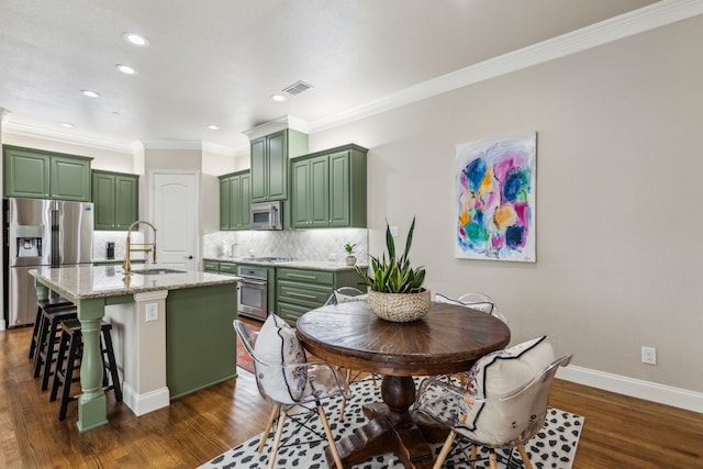828 Lake Vista Pl, Coppell, TX 75019 - kitchen featuring green cabinetry, appliances with stainless steel finishes, a sink, tasteful backsplash, and ornamental molding