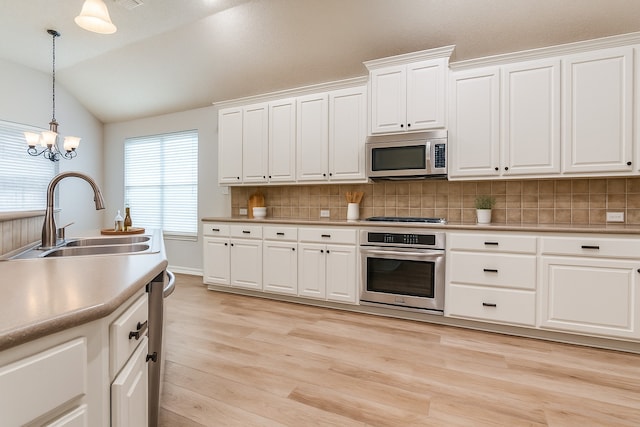 7491 Daffodil Way, Frisco, TX 75033 - kitchen featuring stainless steel appliances, a sink, vaulted ceiling, tasteful backsplash, and pendant lighting