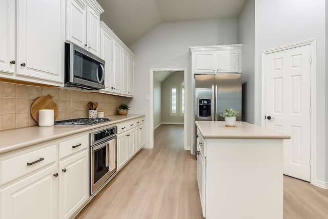 7491 Daffodil Way, Frisco, TX 75033 - kitchen with stainless steel appliances, a kitchen island, tasteful backsplash, light wood-type flooring, and lofted ceiling