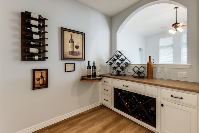7491 Daffodil Way, Frisco, TX 75033 - indoor dry bar with light wood-style flooring, a ceiling fan, arched walkways, and baseboards