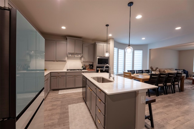 3036 Lionsgate Dr, Argyle, TX 76226 - kitchen with gray cabinetry, a sink, gas cooktop, light wood finished floors, and stainless steel microwave