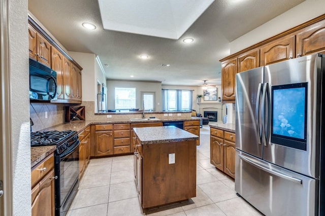 6620 Friendsway Dr, Fort Worth, TX 76137 - kitchen featuring black appliances, tasteful backsplash, a kitchen island, a peninsula, and a fireplace