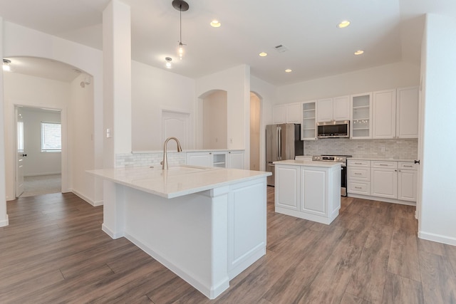 2025 Scott Creek Dr, Little Elm, TX 75068 - kitchen with stainless steel appliances, a sink, arched walkways, backsplash, and a peninsula