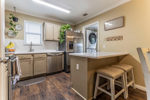 8713 Trinity Vista Trl, Fort Worth, TX 76053 - kitchen featuring appliances with stainless steel finishes, stacked washer / dryer, dark wood-style flooring, tasteful backsplash, and a kitchen breakfast bar