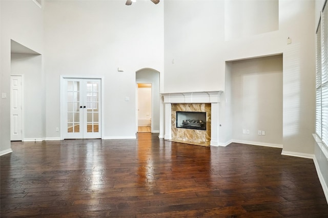 3112 Myrtice Dr, Flower Mound, TX 75022 - unfurnished living room featuring a towering ceiling, arched walkways, wood-type flooring, a ceiling fan, and baseboards