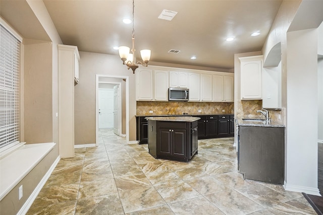 3112 Myrtice Dr, Flower Mound, TX 75022 - kitchen featuring stainless steel microwave, white cabinets, a sink, backsplash, and pendant lighting