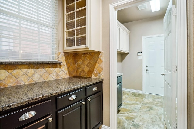 3112 Myrtice Dr, Flower Mound, TX 75022 - kitchen with white cabinets, tasteful backsplash, dark stone countertops, baseboards, and glass insert cabinets