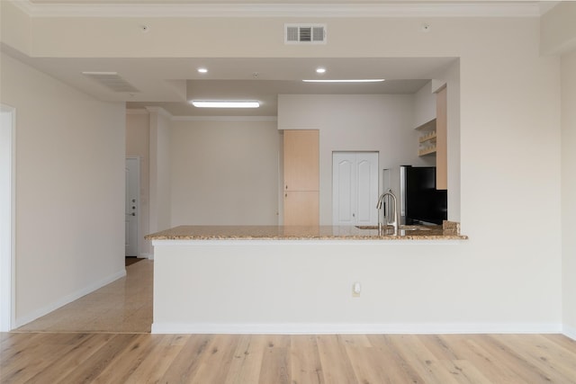 3225 Turtle Creek Blvd Unit 1012, Dallas, TX 75219 - kitchen with freestanding refrigerator, a sink, light stone counters, crown molding, and light wood-style flooring