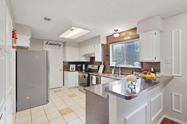 1019 W Lovers Ln W, Arlington, TX 76013 - kitchen featuring appliances with stainless steel finishes, a peninsula, decorative backsplash, dark countertops, and a textured ceiling