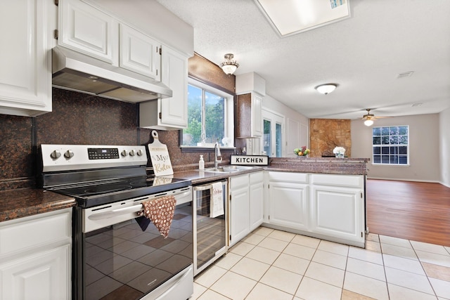 1019 W Lovers Ln W, Arlington, TX 76013 - kitchen featuring electric stove, under cabinet range hood, wine cooler, a peninsula, and healthy amount of natural light