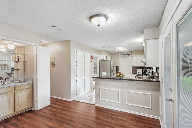 1019 W Lovers Ln W, Arlington, TX 76013 - kitchen with stainless steel refrigerator with ice dispenser, a sink, dark wood finished floors, a peninsula, and a textured ceiling