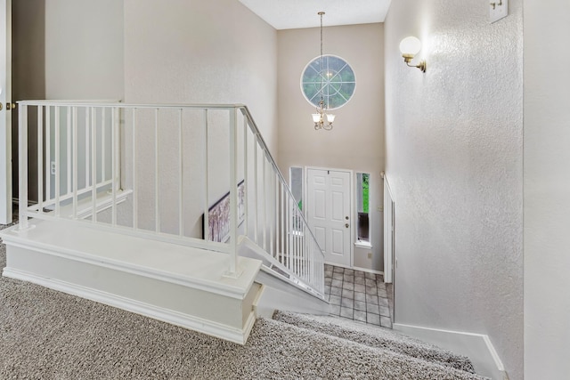 1019 W Lovers Ln W, Arlington, TX 76013 - stairway with a chandelier, a high ceiling, a textured wall, carpet, and baseboards