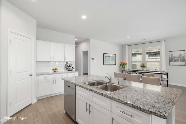 9653 Alderleaf Trl, Fort Worth, TX 76036 - kitchen with a sink, stainless steel dishwasher, backsplash, light wood-style flooring, and an island with sink