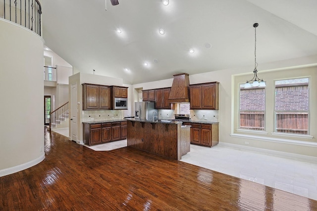 205 Hogue Ln, Wylie, TX 75098 - kitchen with stainless steel appliances, high vaulted ceiling, wood finished floors, baseboards, and custom exhaust hood