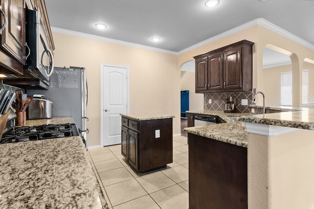 12001 Walden Wood Dr, Fort Worth, TX 76244 - kitchen with arched walkways, stainless steel microwave, a sink, backsplash, and crown molding