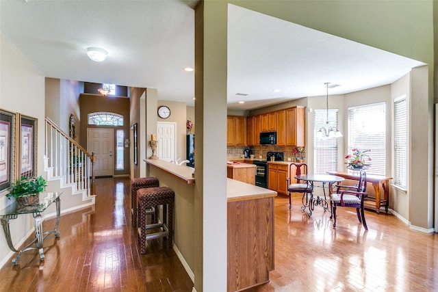 3801 Emerald Park Dr, Corinth, TX 76208 - kitchen featuring black appliances, light wood finished floors, baseboards, light countertops, and backsplash