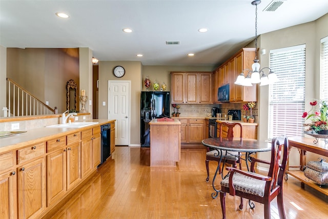 3801 Emerald Park Dr, Corinth, TX 76208 - kitchen featuring a sink, black appliances, a kitchen island, light wood-style flooring, and light countertops