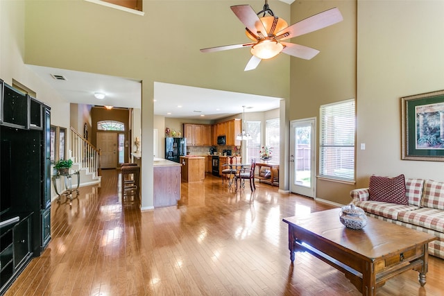 3801 Emerald Park Dr, Corinth, TX 76208 - living room with a towering ceiling, baseboards, stairway, light wood finished floors, and a ceiling fan