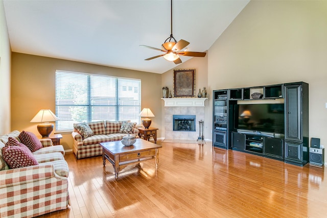 3801 Emerald Park Dr, Corinth, TX 76208 - living area featuring ceiling fan, a tiled fireplace, wood finished floors, baseboards, and high vaulted ceiling