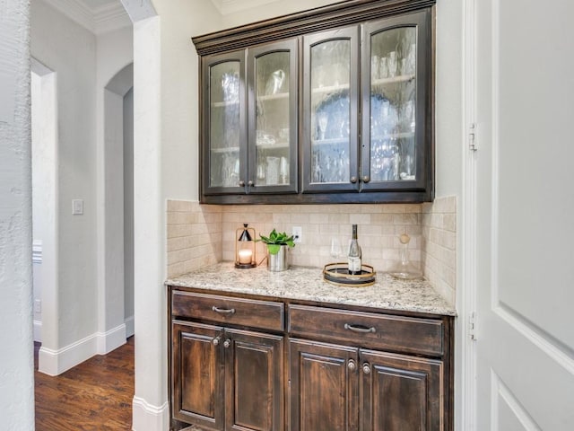 1221 Morris Dr, Keller, TX 76248 - indoor dry bar featuring arched walkways, decorative backsplash, dark wood finished floors, ornamental molding, and baseboards