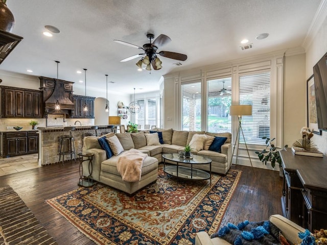 1221 Morris Dr, Keller, TX 76248 - living room featuring ceiling fan, crown molding, dark wood-type flooring, recessed lighting, and a textured ceiling