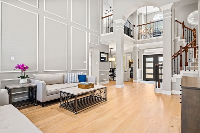 2600 Shadow Hill Ln, Plano, TX 75093 - living room featuring ornate columns, stairway, arched walkways, light wood-style flooring, and a high ceiling