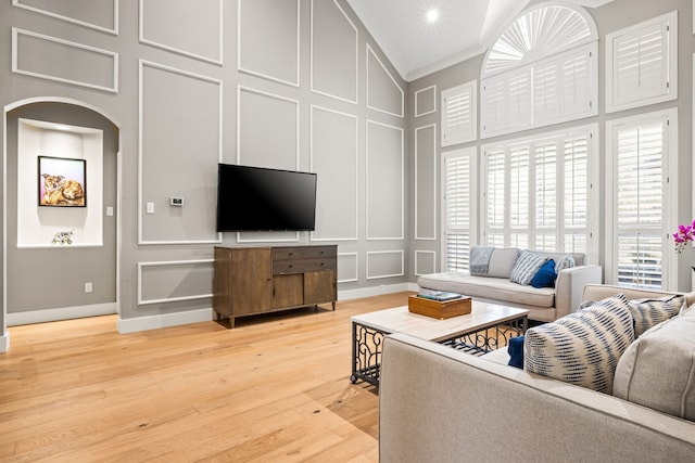 2600 Shadow Hill Ln, Plano, TX 75093 - living room featuring a decorative wall, a high ceiling, ornamental molding, arched walkways, and light wood-style floors