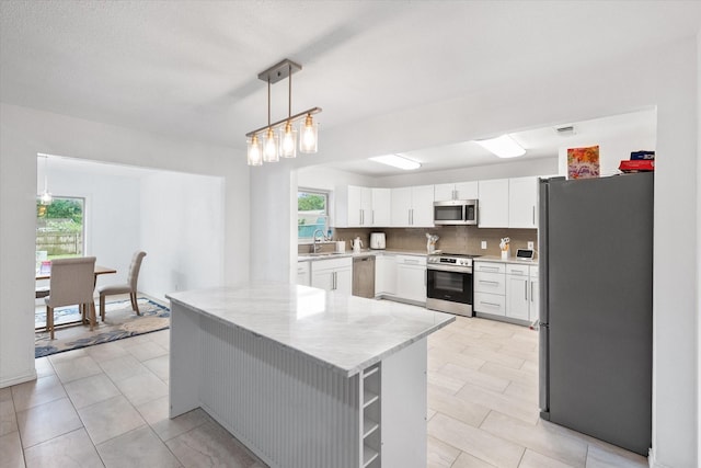 7209 W Cleburne Rd, Fort Worth, TX 76133 - kitchen with appliances with stainless steel finishes, a sink, white cabinetry, hanging light fixtures, and light tile patterned floors
