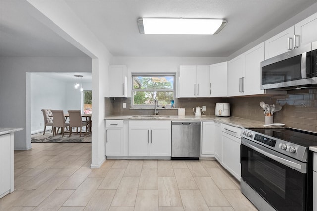 7209 W Cleburne Rd, Fort Worth, TX 76133 - kitchen featuring stainless steel appliances, a sink, backsplash, and white cabinetry