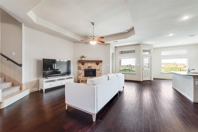 9641 Calaveras Rd, Fort Worth, TX 76177 - living area with a tray ceiling, a ceiling fan, a fireplace, dark wood-style flooring, and recessed lighting