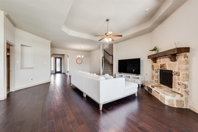9641 Calaveras Rd, Fort Worth, TX 76177 - living room featuring a tray ceiling, a fireplace, stairs, arched walkways, and dark wood finished floors