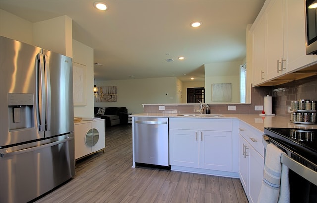 1438 Ganado Dr, Forney, TX 75126 - kitchen featuring stainless steel appliances, open floor plan, a peninsula, white cabinets, and a sink