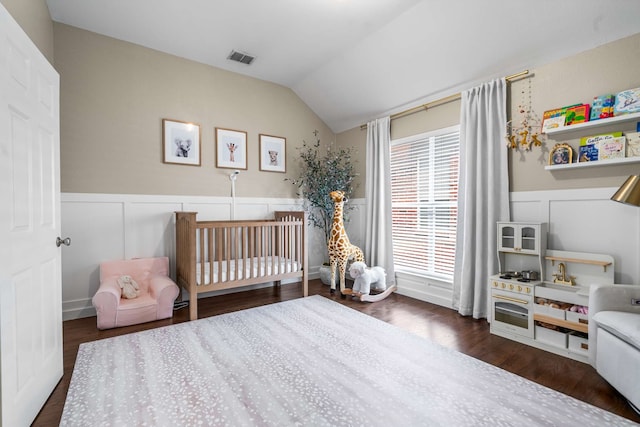 2917 Hallsville St, Dallas, TX 75204 - bedroom featuring vaulted ceiling, a decorative wall, wood finished floors, a wainscoted wall, and a nursery area