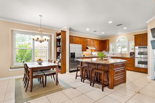 3601 Whitehaven Dr, Plano, TX 75093 - kitchen with appliances with stainless steel finishes, under cabinet range hood, a kitchen island, a chandelier, and brown cabinets