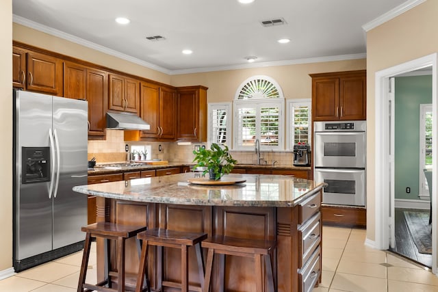 3601 Whitehaven Dr, Plano, TX 75093 - kitchen with stainless steel appliances, under cabinet range hood, a sink, light tile patterned flooring, and a center island