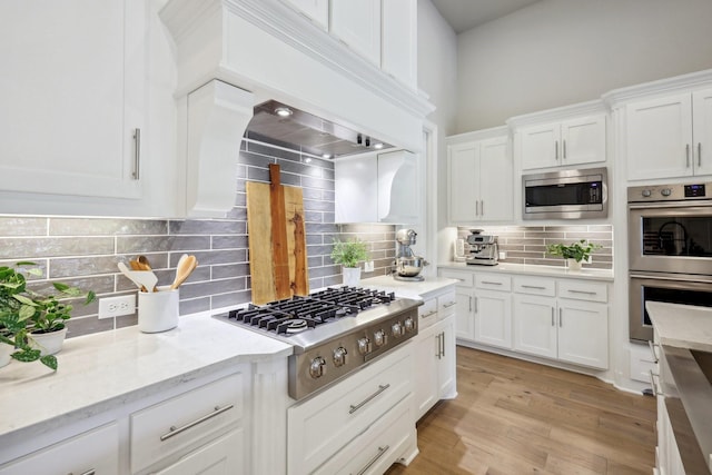 830 Country Brook Ln, Prosper, TX 75078 - kitchen featuring stainless steel appliances, white cabinets, tasteful backsplash, light stone counters, and light wood finished floors