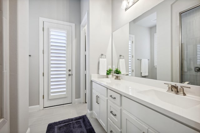 830 Country Brook Ln, Prosper, TX 75078 - bathroom featuring double vanity, baseboards, tiled shower, tile patterned flooring, and plenty of natural light