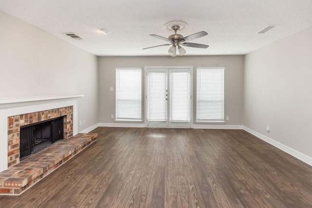 2502 Lake Valley Dr, Garland, TX 75040 - unfurnished living room featuring baseboards, ceiling fan, wood finished floors, a brick fireplace, and a textured ceiling