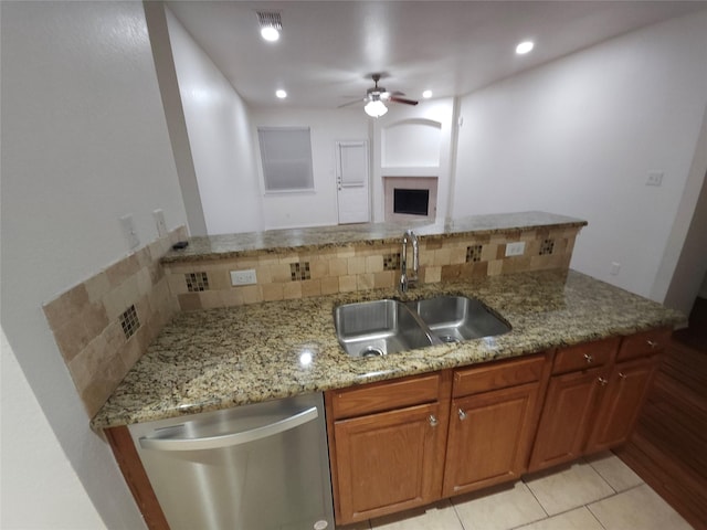 4026 Carrington Dr, Garland, TX 75043 - kitchen featuring stainless steel dishwasher, a sink, ceiling fan, tasteful backsplash, and light stone counters