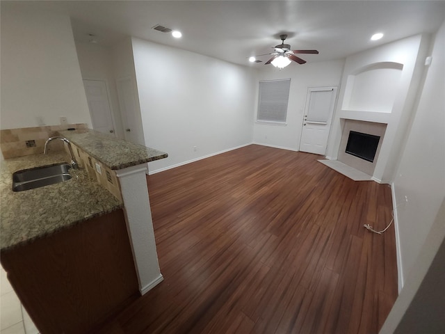 4026 Carrington Dr, Garland, TX 75043 - unfurnished living room with a sink, ceiling fan, a fireplace with flush hearth, dark wood-style floors, and baseboards