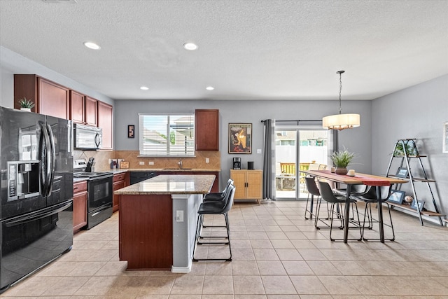 9129 Blackstone Dr, Providence Village, TX 76227 - kitchen with black appliances, tasteful backsplash, a kitchen breakfast bar, healthy amount of natural light, and recessed lighting