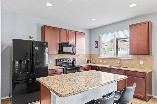 9129 Blackstone Dr, Providence Village, TX 76227 - kitchen with black appliances, a sink, a kitchen island, a kitchen bar, and light stone countertops