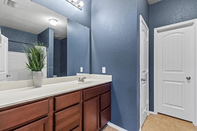9129 Blackstone Dr, Providence Village, TX 76227 - bathroom featuring a textured wall, vanity, tile patterned floors, and baseboards