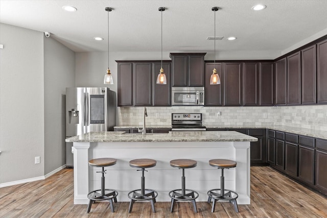 2132 Dewitt Ln, Providence Village, TX 76227 - kitchen with appliances with stainless steel finishes, a sink, dark brown cabinets, backsplash, and a center island with sink