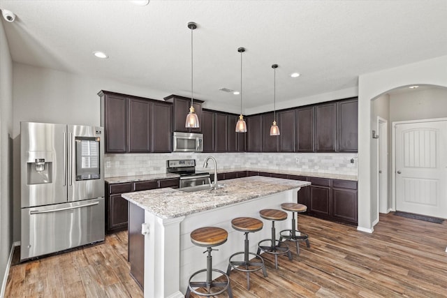 2132 Dewitt Ln, Providence Village, TX 76227 - kitchen with appliances with stainless steel finishes, a sink, arched walkways, dark brown cabinetry, and recessed lighting