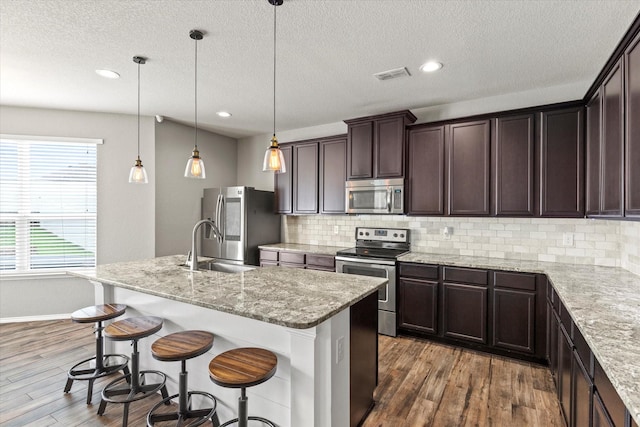 2132 Dewitt Ln, Providence Village, TX 76227 - kitchen with stainless steel appliances, dark brown cabinetry, tasteful backsplash, wood finished floors, and a sink