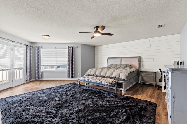 2132 Dewitt Ln, Providence Village, TX 76227 - bedroom with wood finished floors, a textured ceiling, ceiling fan, and wood walls