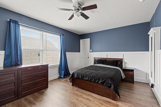 2132 Dewitt Ln, Providence Village, TX 76227 - bedroom featuring wood finished floors, wainscoting, a textured ceiling, a ceiling fan, and a textured wall