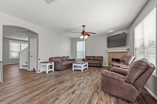 2132 Dewitt Ln, Providence Village, TX 76227 - living area with a tiled fireplace, ceiling fan, wood finished floors, and arched walkways